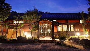 A traditional Japanese building with a covered entrance, wooden flooring, and a gravel pathway leading to the door.