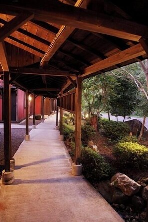 A covered walkway with wooden beams, leading to a building with a red exterior. - Yufuin Onsen Yufuin Ryoan Wazanho (Yufu)