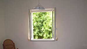A bedroom with a bed, a chair, a window, and a hanging light fixture. - HOUSE FOR RENT IN THE COUNTRYSIDE  (MONTE GIOVE)