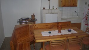 A compact kitchen with wooden cabinets, a sink, and a dining table with chairs. - HOUSE FOR RENT IN THE COUNTRYSIDE  (MONTE GIOVE)