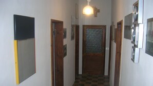 A narrow hallway with checkered flooring, wooden doors, and a wall-mounted light fixture. - HOUSE FOR RENT IN THE COUNTRYSIDE  (MONTE GIOVE)
