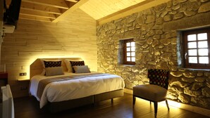 A cozy bedroom with a stone wall, a wooden ceiling, a bed with pillows, a chair, and a window. - Hôtel Restaurant Le Vieux Logis (Yvoire)