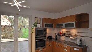 A modern kitchen with wooden cabinets, stainless steel appliances, and a large window.