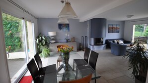 A modern living room with a glass dining table, black chairs, and a blue sofa.