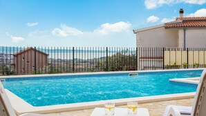 Une piscine à l’eau d’un bleu cristallin, entourée d’une clôture et offrant une vue panoramique.