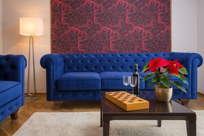 A living room with a blue sofa, a coffee table with a chess set, a bottle, and a potted plant. - Vacation house MATER (Split)
