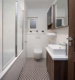 A compact bathroom with a glass shower enclosure, a white toilet, a sink with a mirror, and a small window above the toilet. - Vacation house MATER (Split)