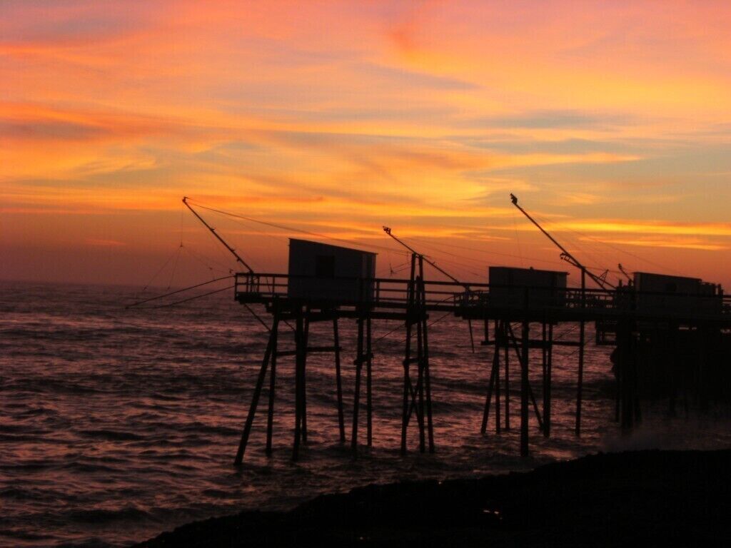 A pier with fishing equipment silhouetted against a sunset.