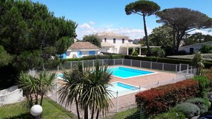 A swimming pool surrounded by a fenced garden with various plants and trees.