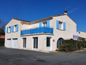 Un edificio de dos pisos con balcón, garaje y una puerta con el número 21.