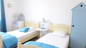 A twin room with two beds, a small table, a lamp, a wardrobe, and a mirror.