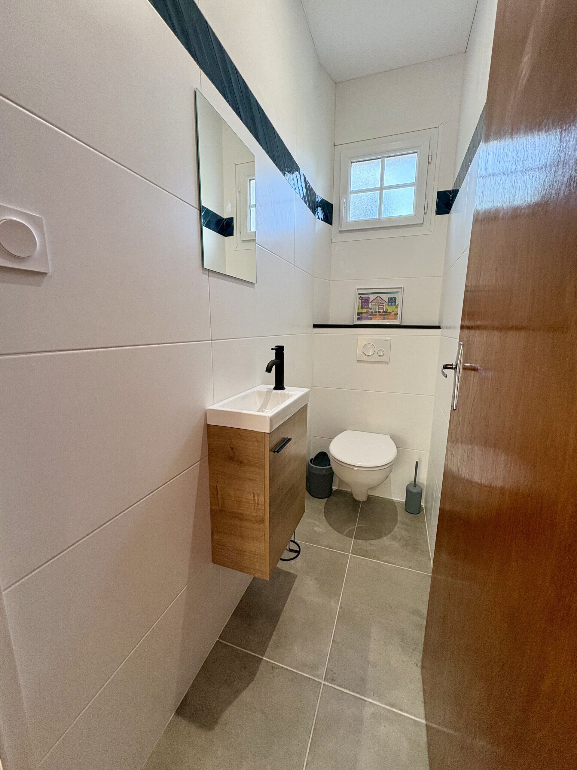 A bathroom with a white sink, a mirror, a toilet, and a window.