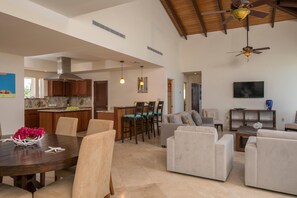 A spacious living area with a dining table, sofas, and a kitchen in the background.