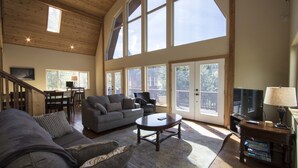 A spacious living room with a high ceiling, large windows, a fireplace, and a cozy seating area. - Carlin Bay Retreat on Lake Coeur d'Alene  (Harrison)
