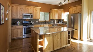 A modern kitchen with wooden cabinets, stainless steel appliances, and a granite countertop. - Carlin Bay Retreat on Lake Coeur d'Alene  (Harrison)