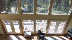 A spacious room with a large window, a sofa, a skateboard, and a dining table. - Carlin Bay Retreat on Lake Coeur d'Alene  (Harrison)