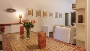 A dining area with a patterned table, white chairs, a vase with flowers, and framed artwork on the wall. - Unique opportunity to live in a Renaissance palace (Roma)