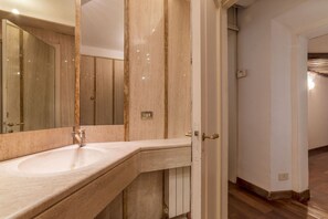 A bathroom with a large mirror, a sink, and a door leading to another room. - Unique opportunity to live in a Renaissance palace (Roma)