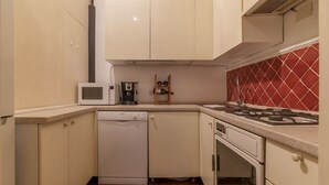A compact kitchen with white cabinets, a microwave, a dishwasher, a gas stove, and a red-tiled backsplash. - Unique opportunity to live in a Renaissance palace (Roma)