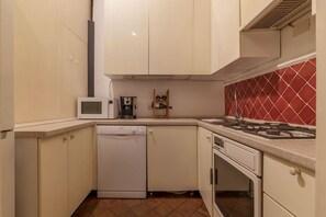 A compact kitchen with white cabinets, a microwave, a dishwasher, a gas stove, and a red-tiled backsplash. - Unique opportunity to live in a Renaissance palace (Roma)