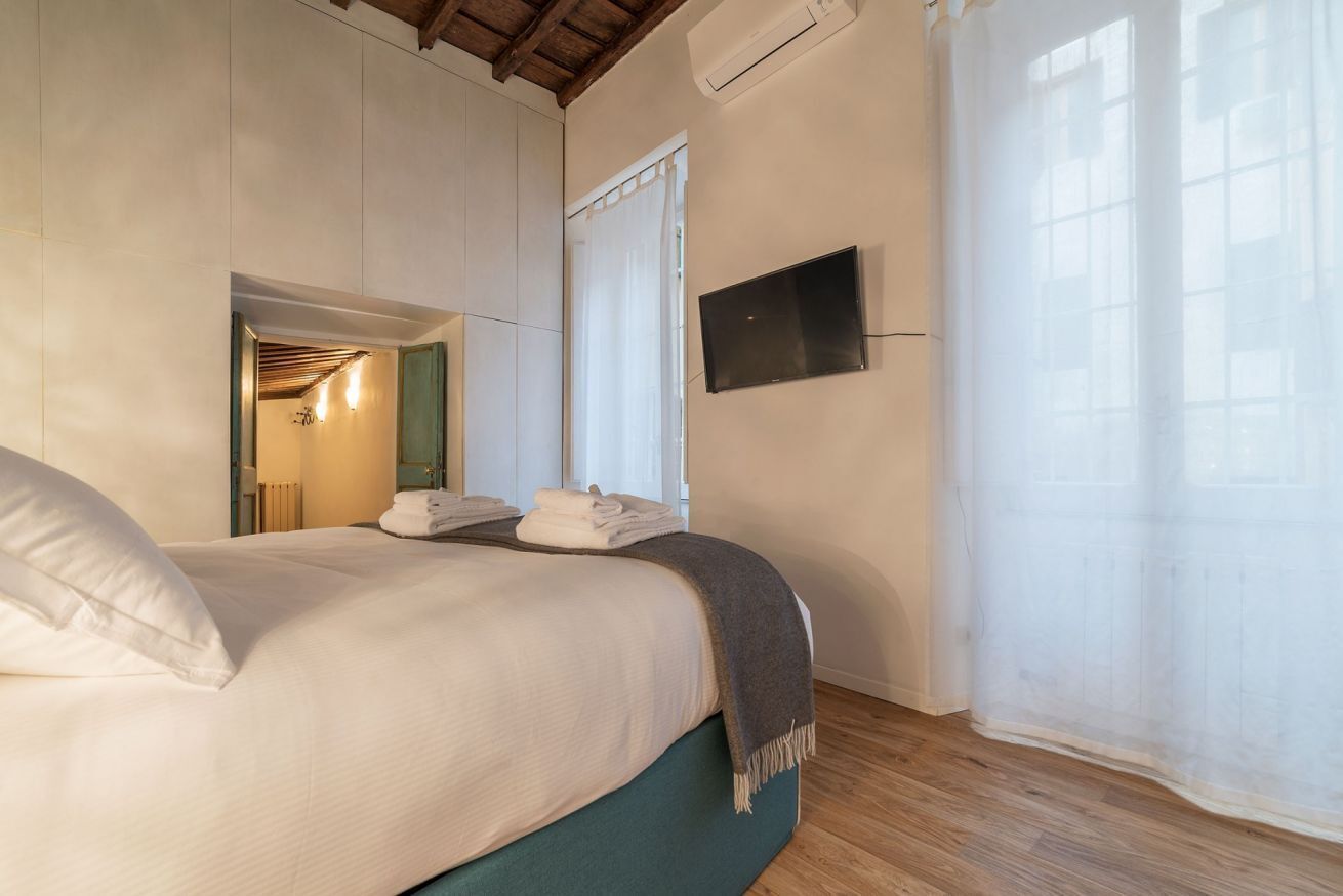 Un dormitorio con cama, televisor y ventana con cortinas.