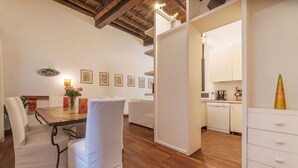 A modern interior with a dining area, white furniture, wooden flooring, and a kitchen visible through an open door. - Unique opportunity to live in a Renaissance palace (Roma)
