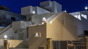 A modern building with a staircase leading to a gated entrance, a sign with a logo, and a security gate. - Petra Bianca (Ugento)