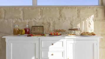 A buffet setup with various food items and drinks on a white cabinet against a textured wall.
