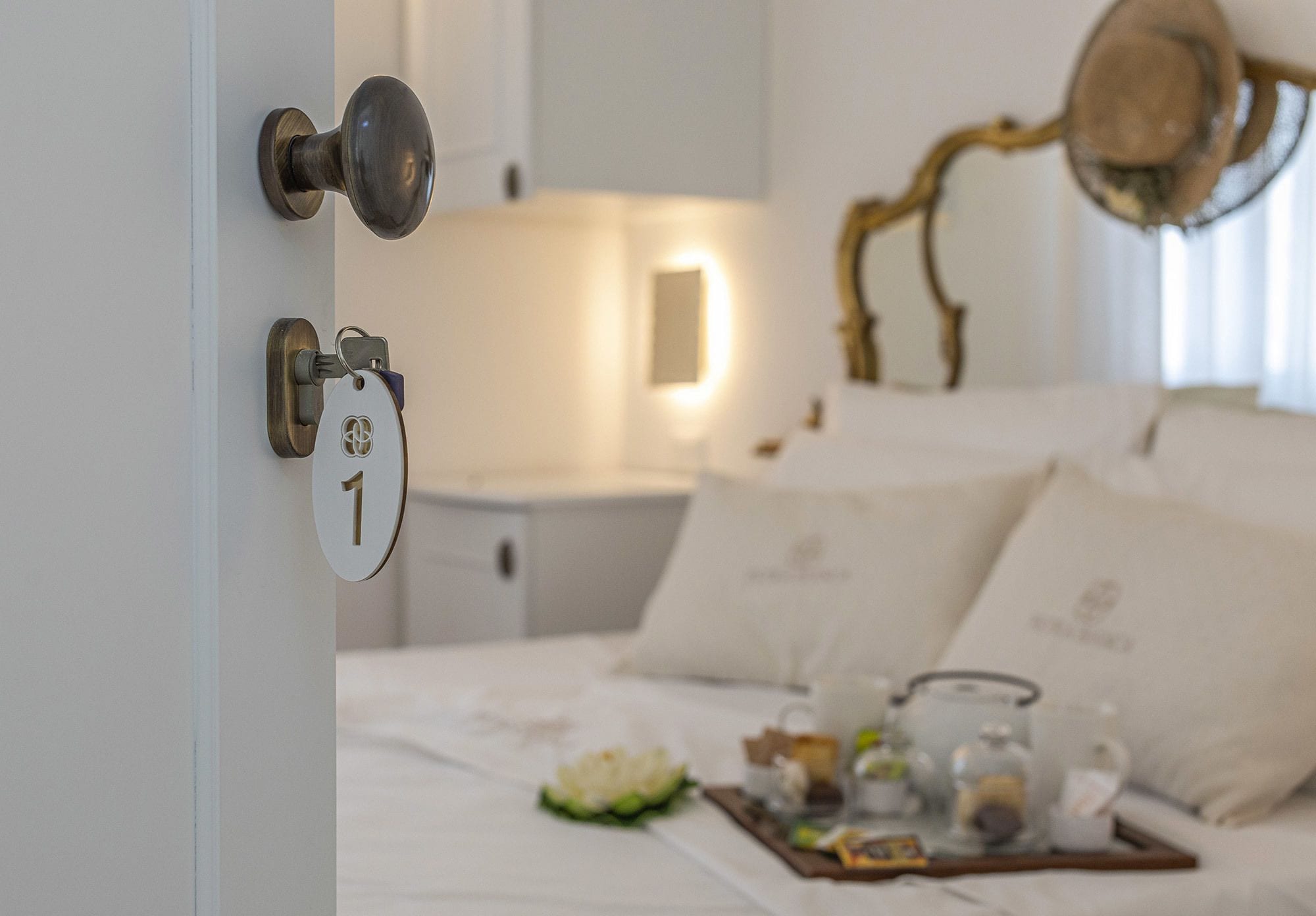 Un dormitorio con cama, mesita de noche, lámpara y una bandeja con alimentos.