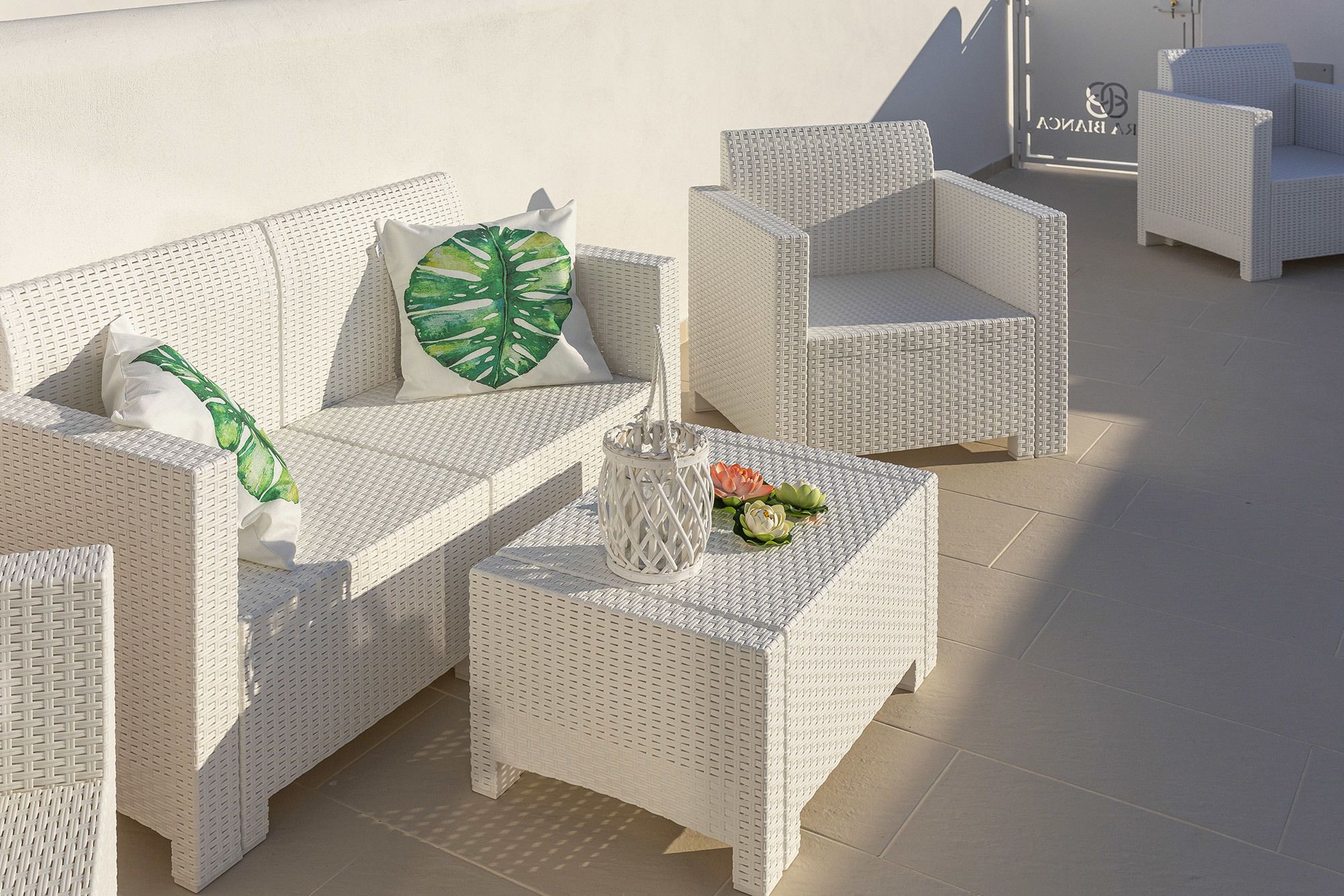 Ein Set aus weißem Wicker-Möbel, darunter Stühle und ein kleiner Tisch, mit einer strukturierten Oberfläche.