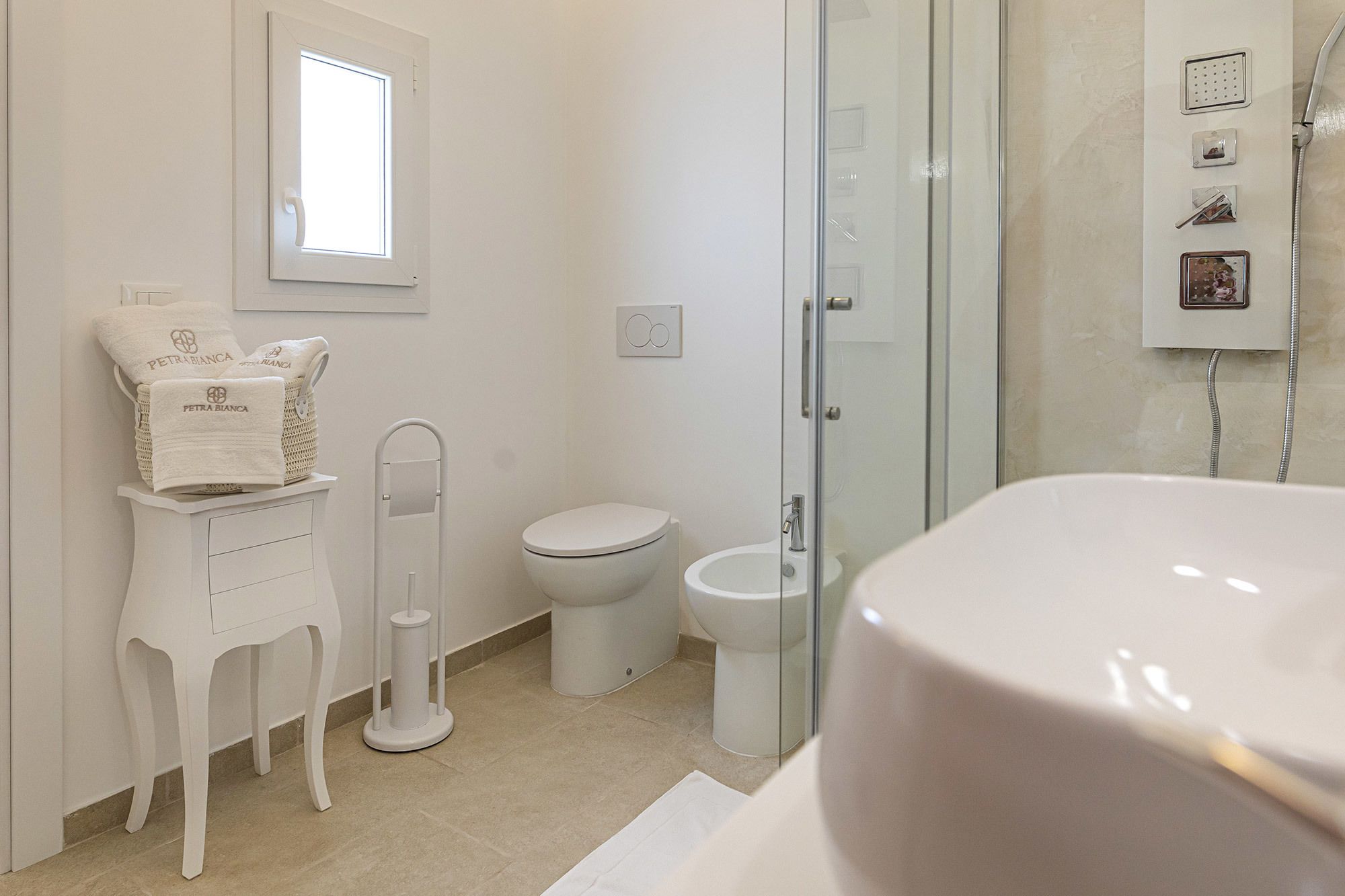 A modern bathroom with a toilet, bidet, and a glass shower enclosure.