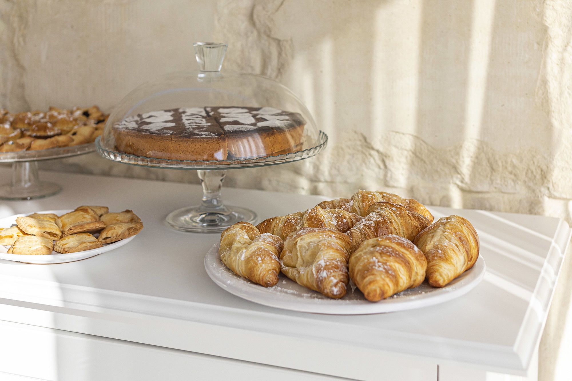 Een dessertpresentatie met gebakjes en een taart op een witte tafel.