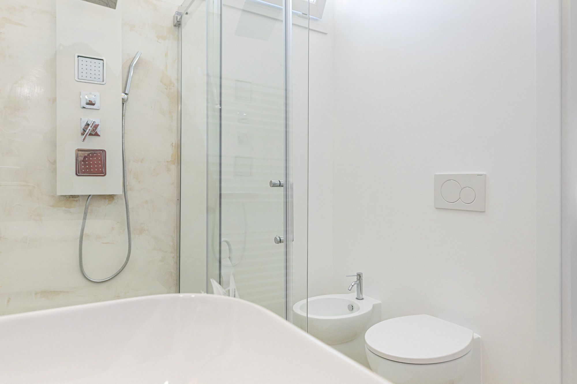Un baño moderno con ducha de vidrio, bañera independiente, lavabo e inodoro.