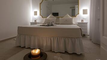 A neatly made bed with a white duvet, a bedside table with a lamp, and a mirror above the bed.