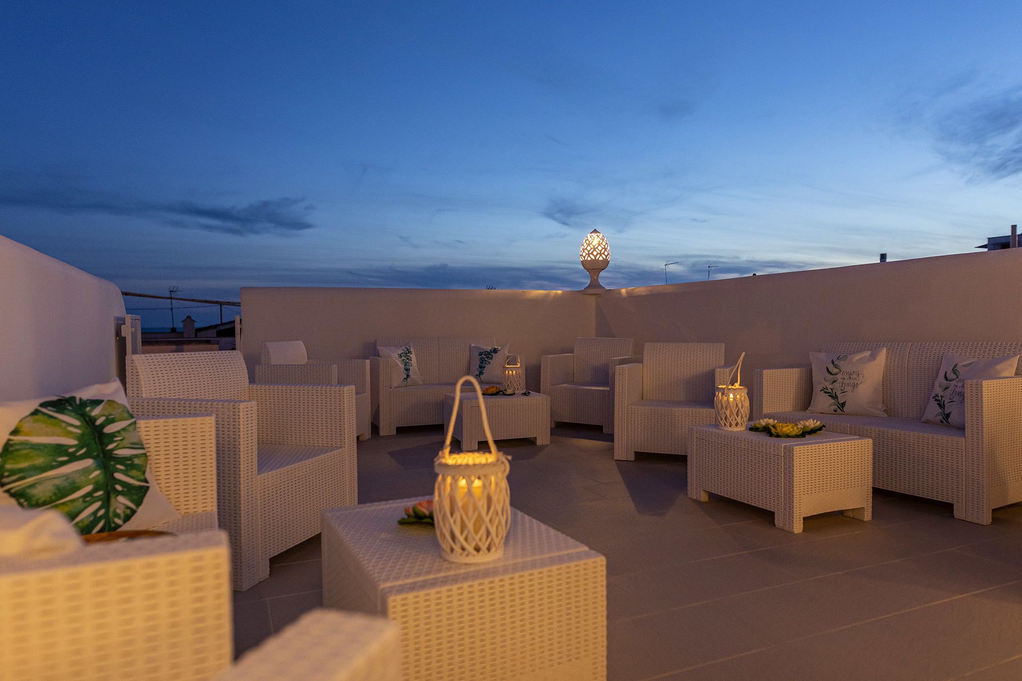Una terraza en la azotea con mobiliario de mimbre, una lámpara decorativa y vistas al cielo.