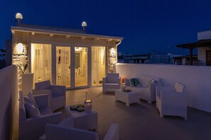 A rooftop terrace with white wicker furniture, a dining area with white curtains, and decorative lighting. - Petra Bianca (Ugento)