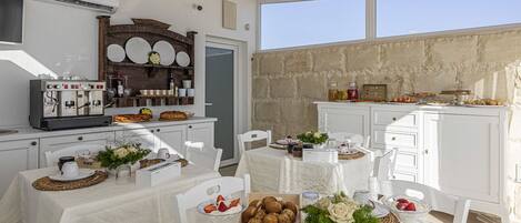 A dining area with white tables, a coffee machine, and a stone wall.