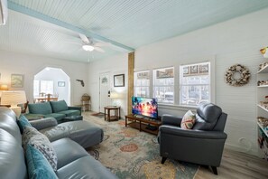 A living room with a sofa, armchairs, a TV, and a ceiling fan.