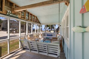 Un espacio de estar al aire libre con techo, mobiliario de madera, piscina y vistas a la playa.