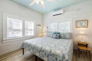 A bedroom with a bed, two bedside tables, a ceiling fan, and a window with blinds.