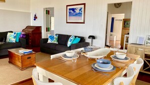 A dining area with a wooden table set for four, surrounded by white chairs. - Burrum Beach House-Waterfront-Private Jetty-2BR (Burrum Heads)