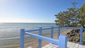 A coastal walkway with a blue railing, a rocky shoreline, and a clear view of the sea. - Burrum Beach House-Waterfront-Private Jetty-2BR (Burrum Heads)