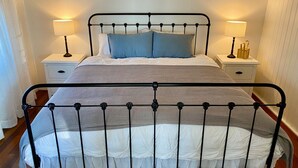 A bed with a metal frame, white bedding, and two bedside tables with lamps. - Burrum Beach House-Waterfront-Private Jetty-2BR (Burrum Heads)