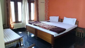 A bedroom with a bed, a small table, and a window with curtains. - Elation Guest House & Musafir Cafe (Ranikhet)