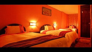A hotel room with three beds, each with a headboard and bedside lamps. - Hotel Margarita (Puno)