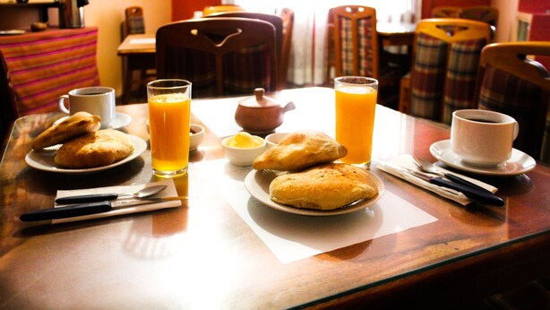 A breakfast table with pastries, orange juice, and a teapot. - Hotel Margarita (Puno)