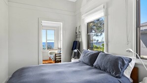 Et soveværelse med seng, et vindue med havudsigt og en dør til en balkon.
