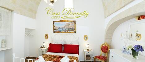 A bedroom with a bed, a chair, a dresser, a mirror, and a painting on the wall.