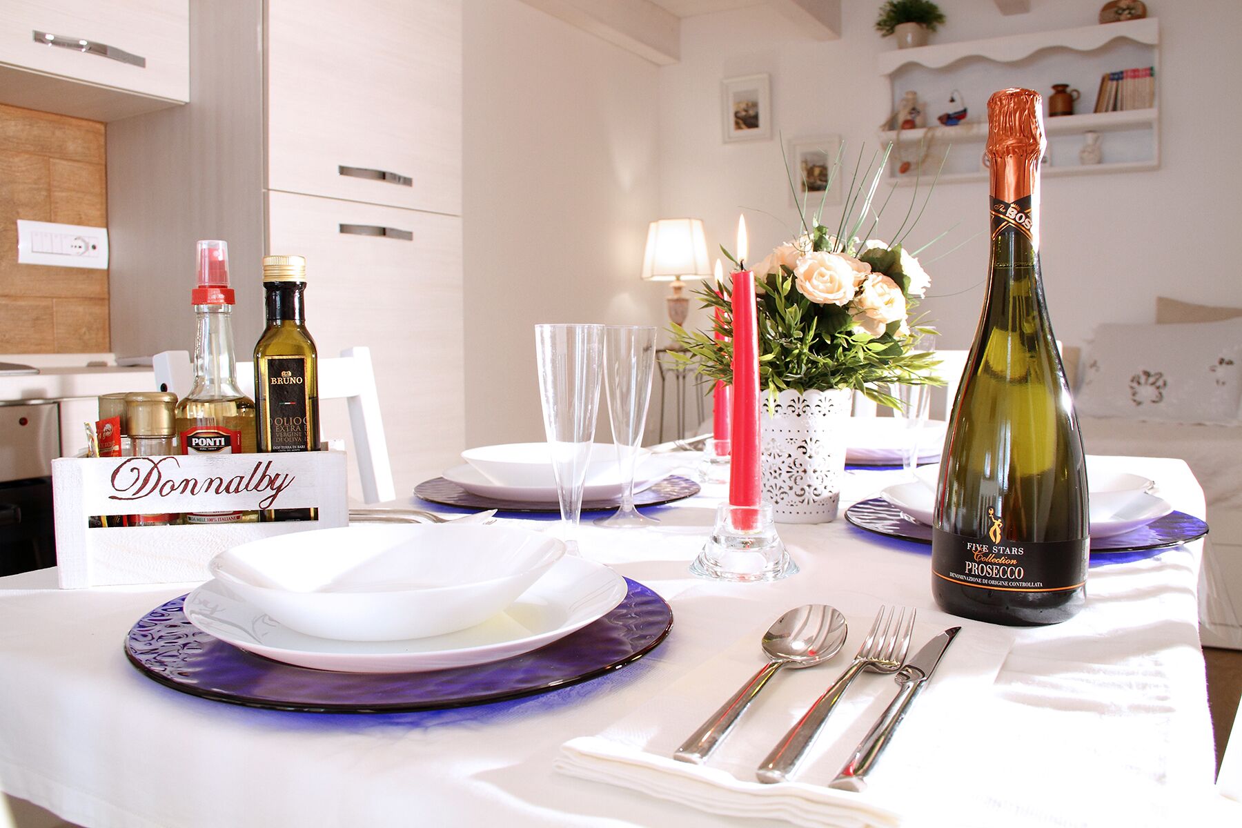 A dining table set with plates, glasses, cutlery, and a bottle of wine.