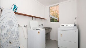 A laundry room with a washing machine, dryer, and a window with a view of greenery. - Beachside Shoal Bay Unit 6 (Shoal Bay)